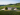 Aerial view of a large vineyard estate with lush vine rows and a central building surrounded by trees under a clear sky.