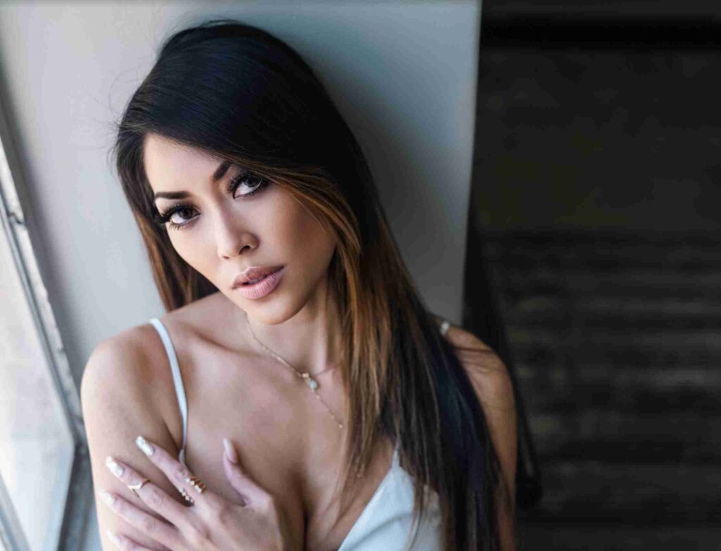 A man in glasses and a blue suit poses with his hands up against a backdrop with text overlays referring to entertainment.