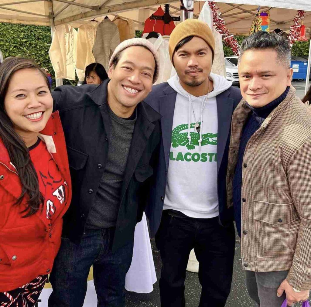 A smiling person sitting on steps wearing a striped shirt and white sneakers.