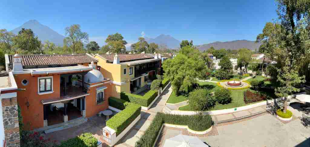 A panoramic view of a landscaped area with colorful houses and mountains in the background under a clear blue sky.