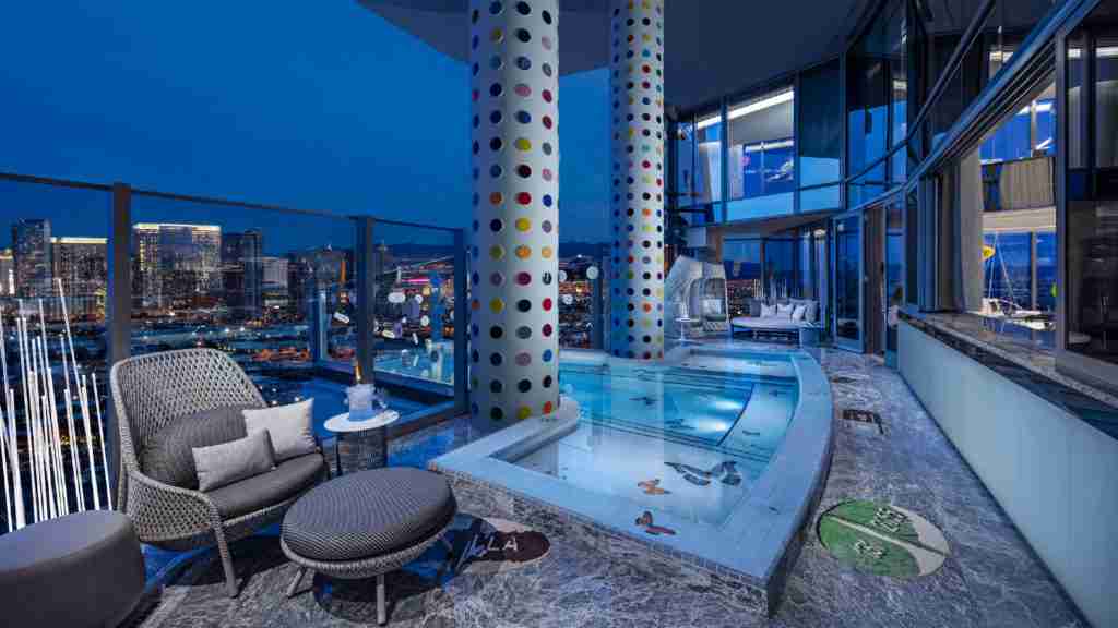 A luxurious night-time penthouse interior featuring an open-concept living area with modern decor, city skyline views, and an integrated glass-enclosed hot tub.