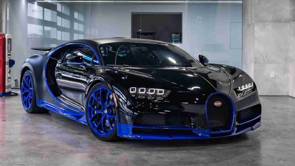 A sleek black Bugatti Chiron sports car with blue accents parked inside a modern showroom.