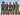 Five men dressed in stylized cowboy attire with hats and boots stand confidently in a desert setting.