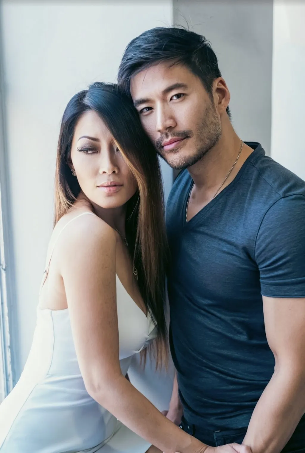 A woman with long dark hair looks over her shoulder with an intense gaze near a blurred foreground element.