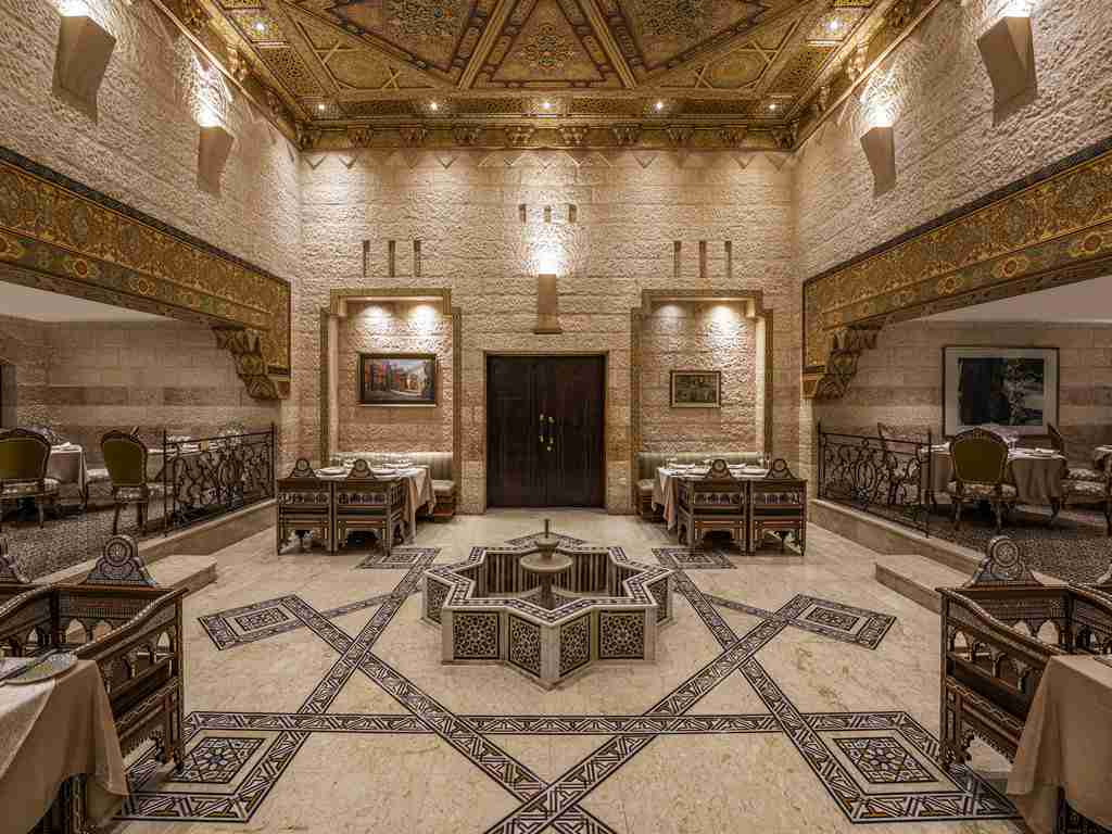 An ornate room featuring intricate floor designs, detailed ceiling patterns, classic furniture, and elegant wall decorations.