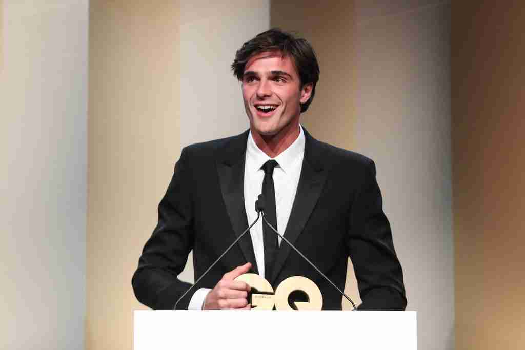An elegant dining room with white tablecloths, red chairs, chandeliers, large windows, and ornate decor.