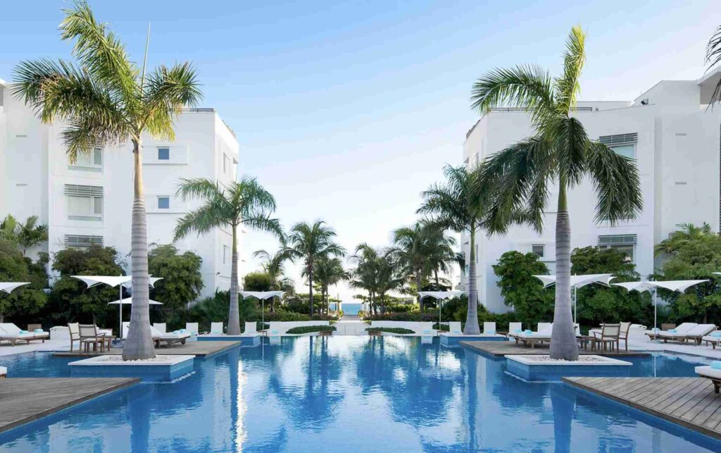 An elegant dining room with white tablecloths, red chairs, chandeliers, large windows, and ornate decor.