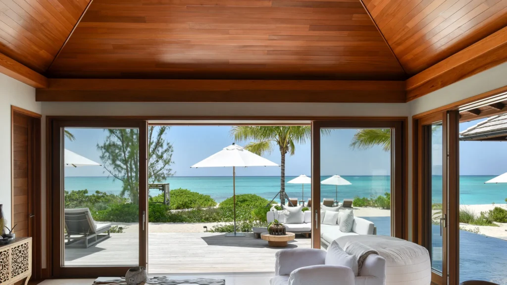 An elegant dining room with white tablecloths, red chairs, chandeliers, large windows, and ornate decor.