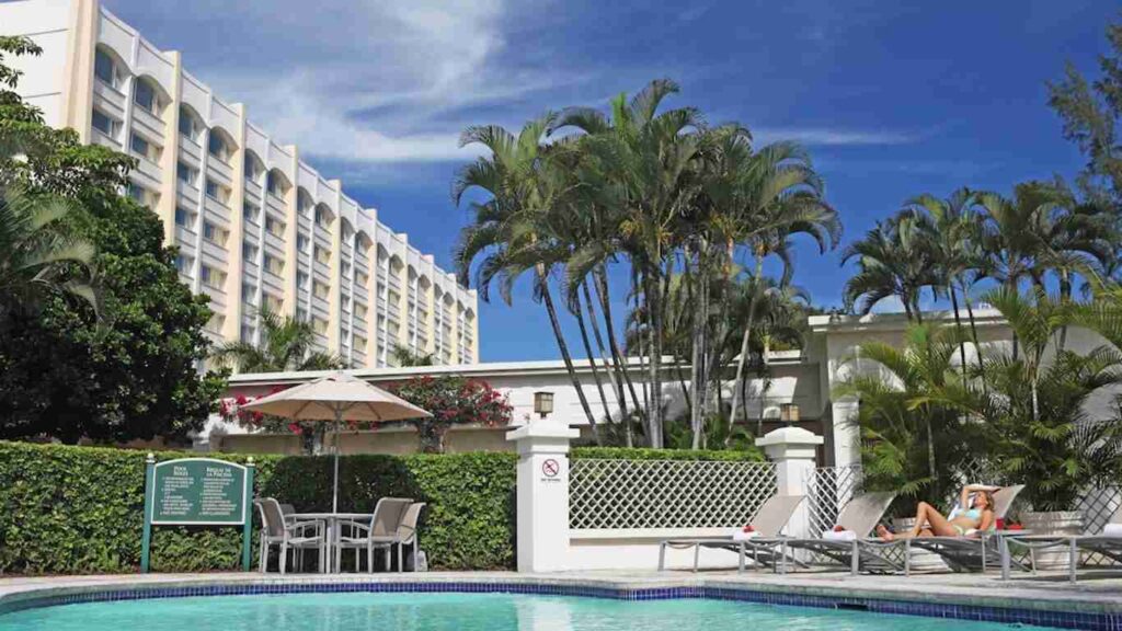 An elegant dining room with white tablecloths, red chairs, chandeliers, large windows, and ornate decor.