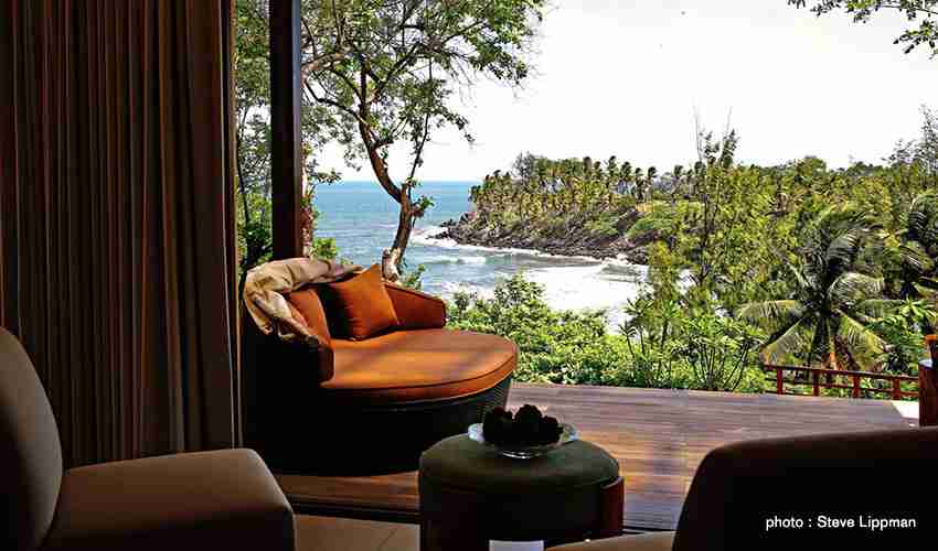 An elegant dining room with white tablecloths, red chairs, chandeliers, large windows, and ornate decor.
