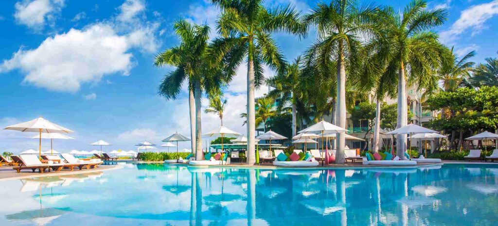 An elegant dining room with white tablecloths, red chairs, chandeliers, large windows, and ornate decor.