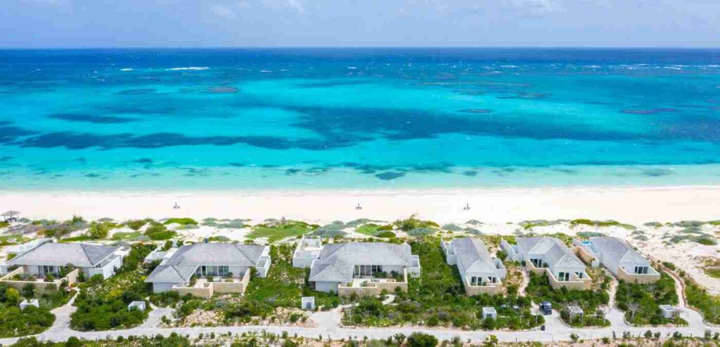 An elegant dining room with white tablecloths, red chairs, chandeliers, large windows, and ornate decor.