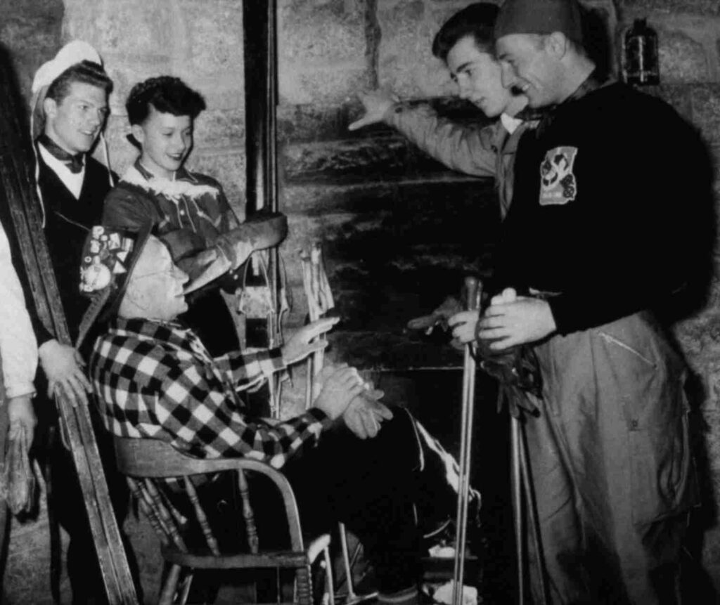 A person is relaxing in a steaming outdoor hot tub with a snowy mountain backdrop under a clear sky.