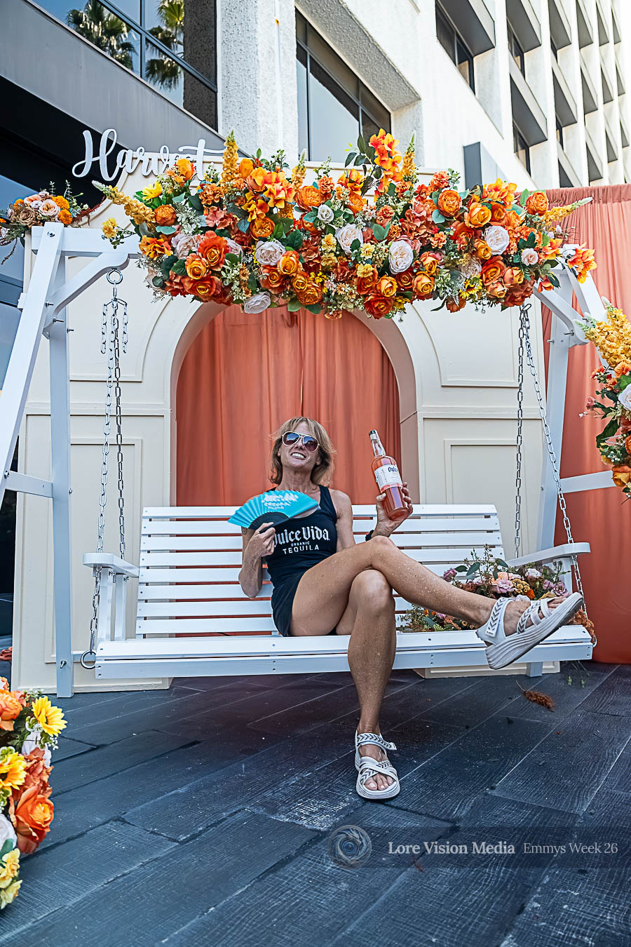 Woman holding wine under flower arch at Harvest Emmy event
