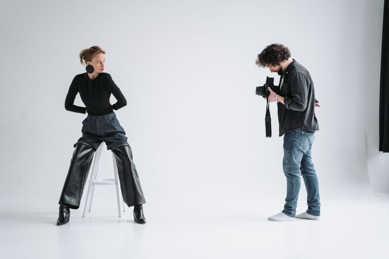 Fashion photographer shooting a model posing on a stool in a Los Angeles studio