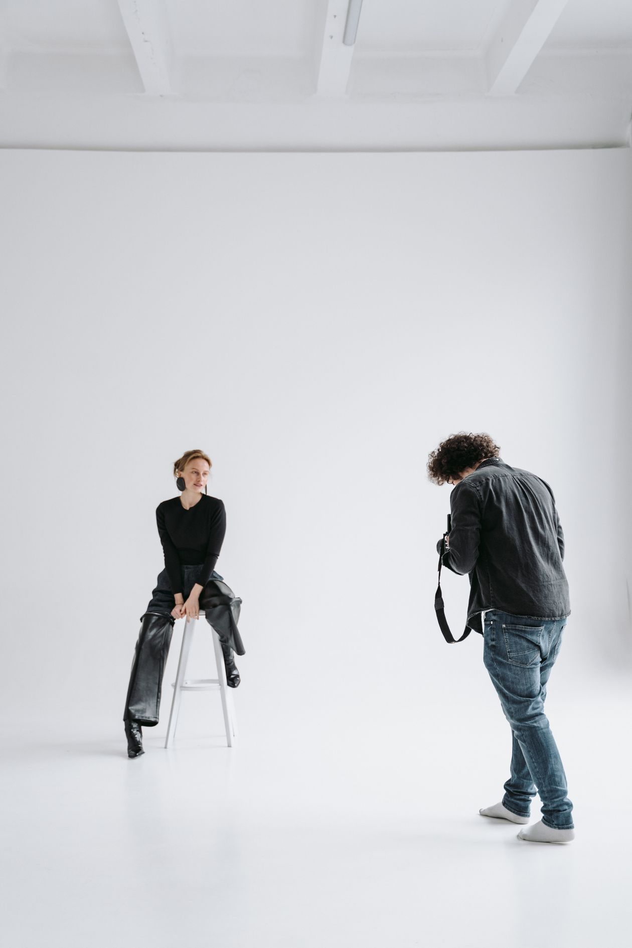 Wide shot of a fashion photographer working with a model on a white cyclorama in Los Angeles