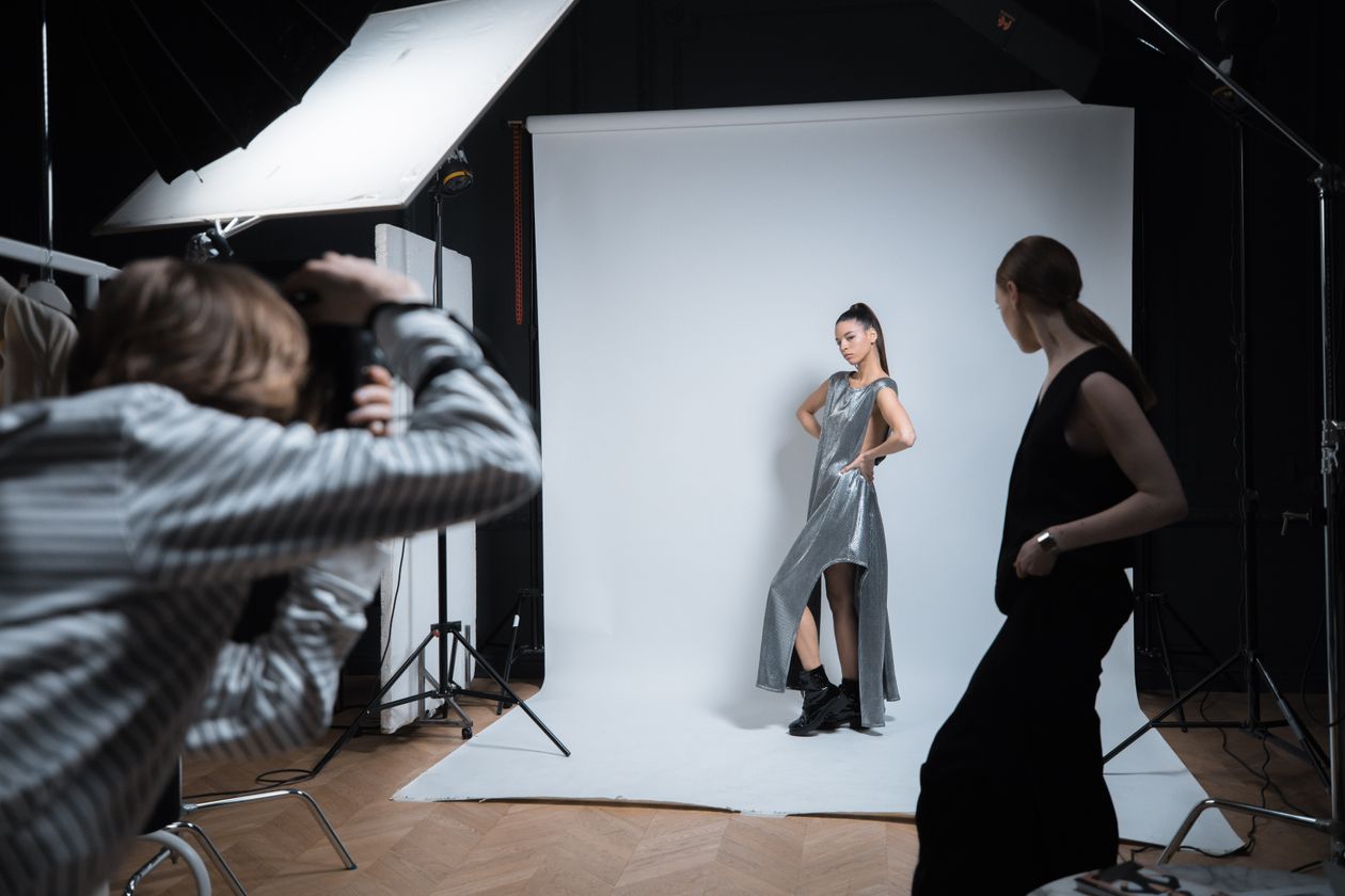 Behind the scenes of a Los Angeles fashion shoot: photographer, model in a metallic dress, stylist on set