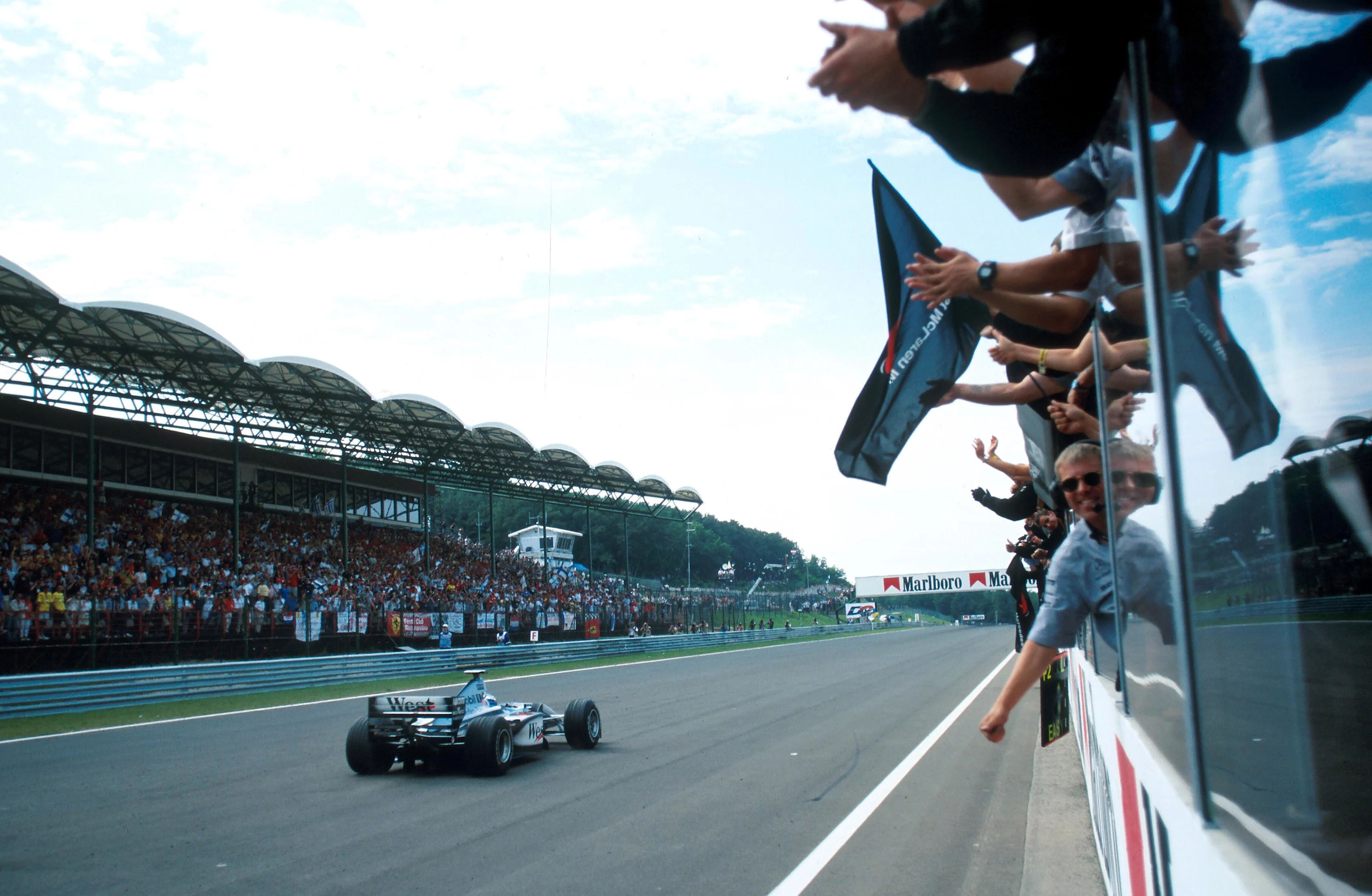 An archive photo from the Hungaroring: a McLaren takes the chequered flag in front of a packed grandstand.