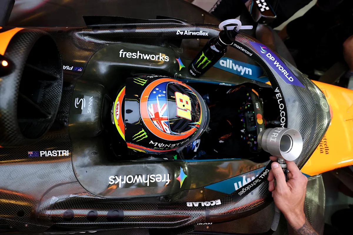 Oscar Piastri in the cockpit of his McLaren, seen from above during a night race, his No. 81 helmet visible.