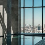 Aman Tokyo 30-metre indoor swimming pool with stone columns and floor-to-ceiling windows overlooking the Tokyo skyline