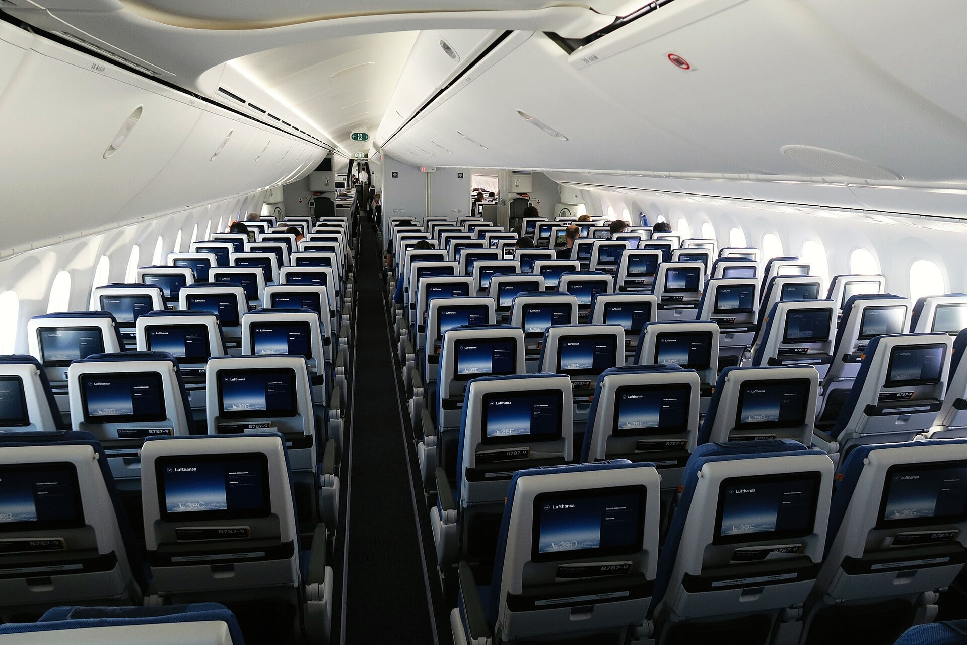 Rows of economy seats with seatback entertainment screens in a Lufthansa Boeing 787 Dreamliner