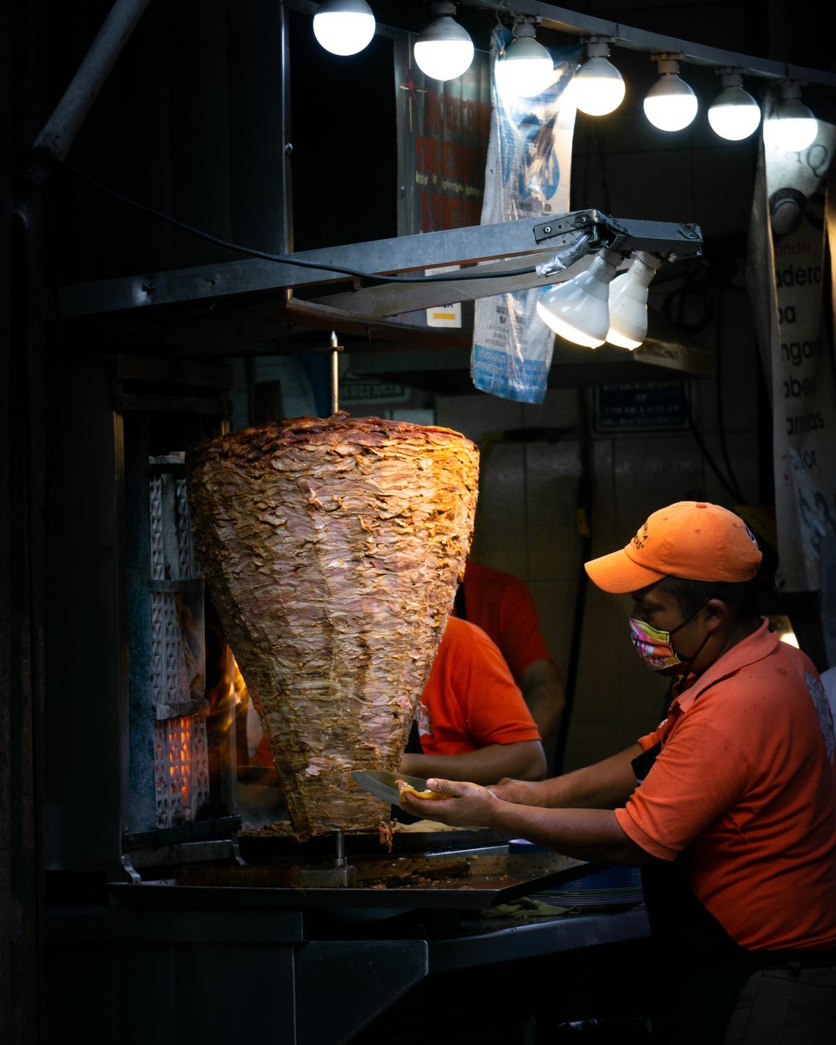 Al pastor meat roasting on a vertical trompo spit at night, the signature of the best tacos in Los Angeles