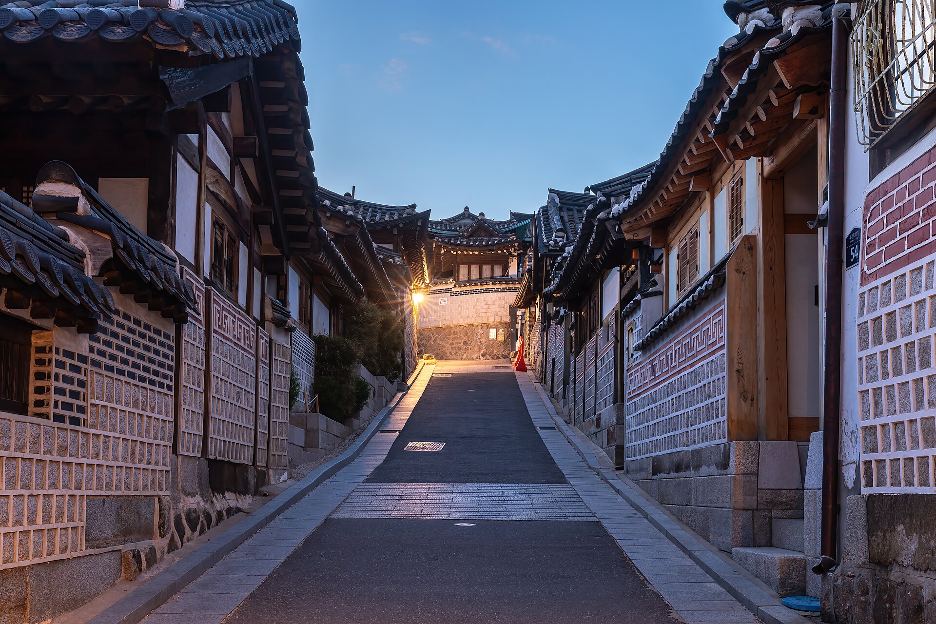 A quiet street of traditional hanok houses in Bukchon Hanok Village, Seoul, glowing at blue hour