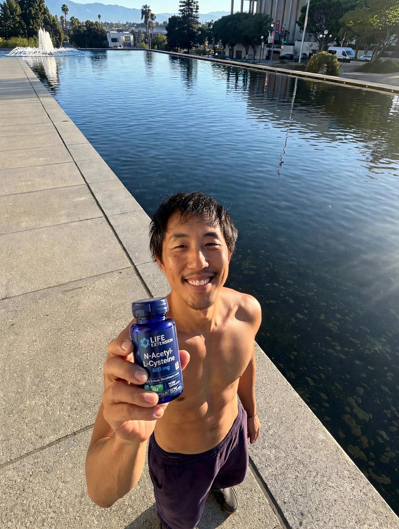 David holding Life Extension NAC bottle in front of the water.