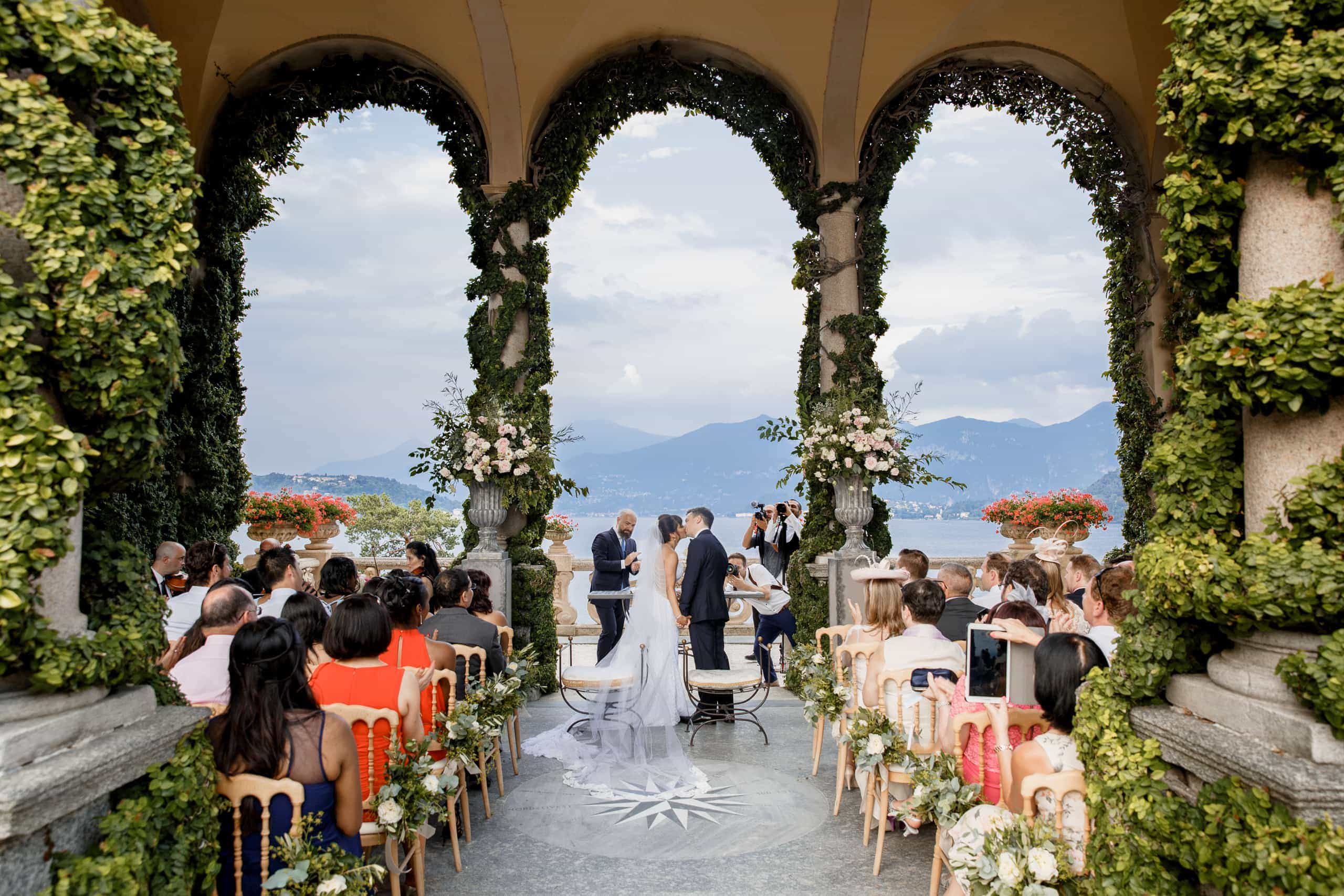 Wedding ceremony under a vine-covered loggia overlooking Lake Como in Italy