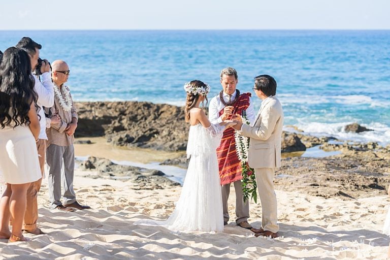 Beach wedding ceremony with the officiant and couple on the sand in Hawaii