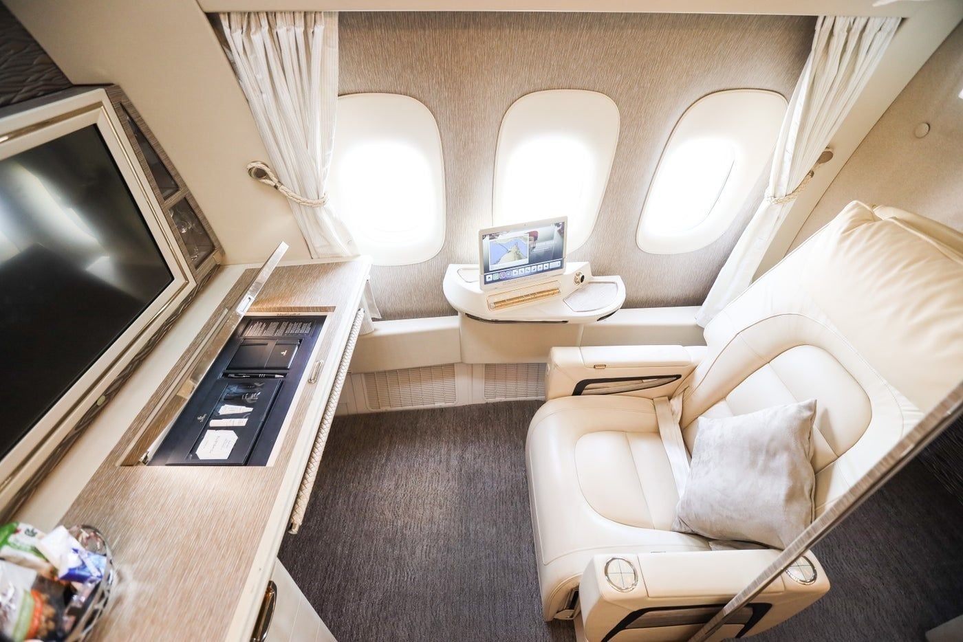 Spacious first class airplane cabin with a lie-flat suite seat beside the window