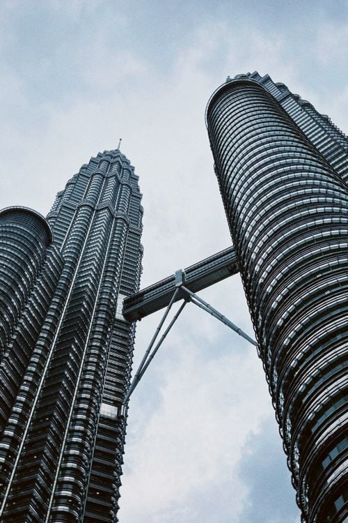 Low-angle view of the Petronas Twin Towers in Kuala Lumpur against a cloudy sky