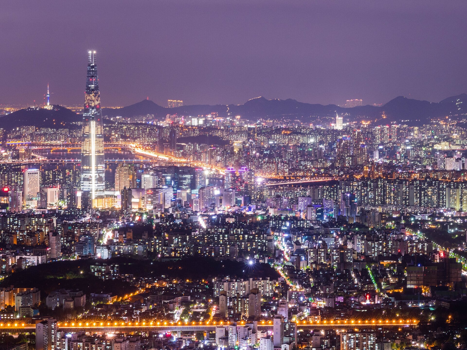 Seoul skyline at night with the illuminated Lotte World Tower rising above the city lights