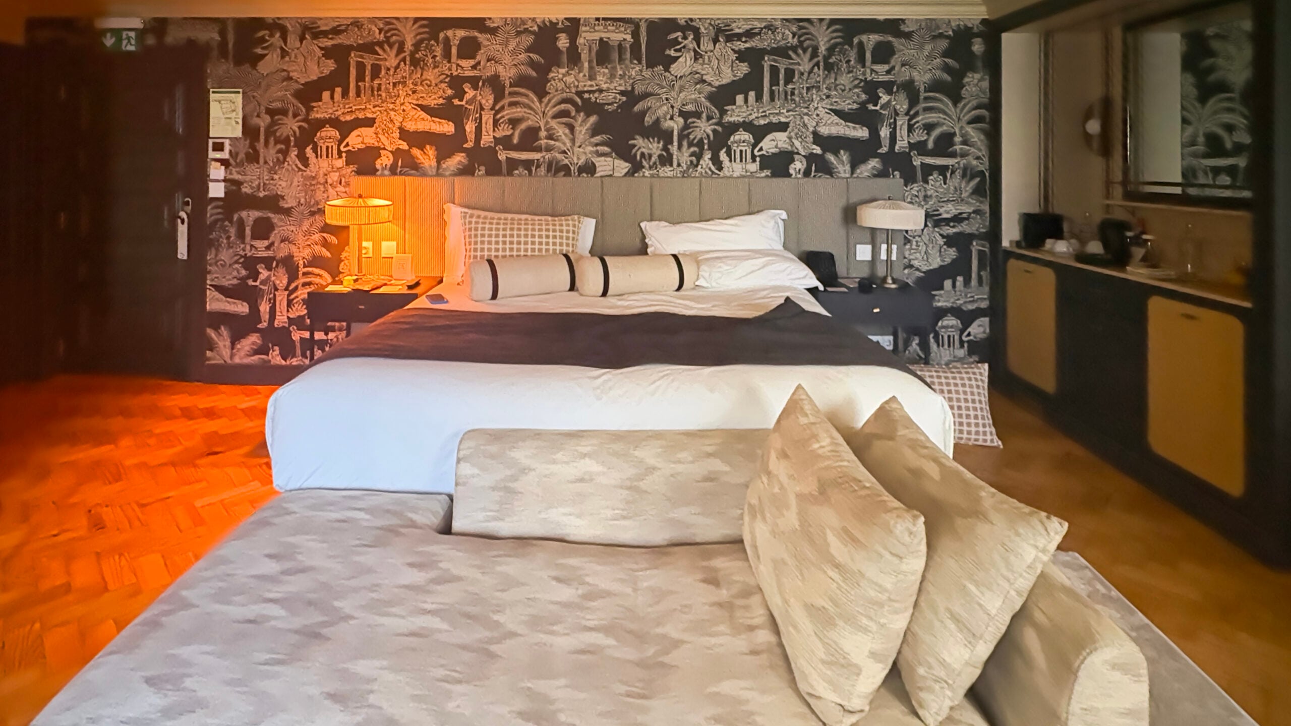 Boutique hotel bedroom with tropical-print wallpaper and white bedding in Lisbon