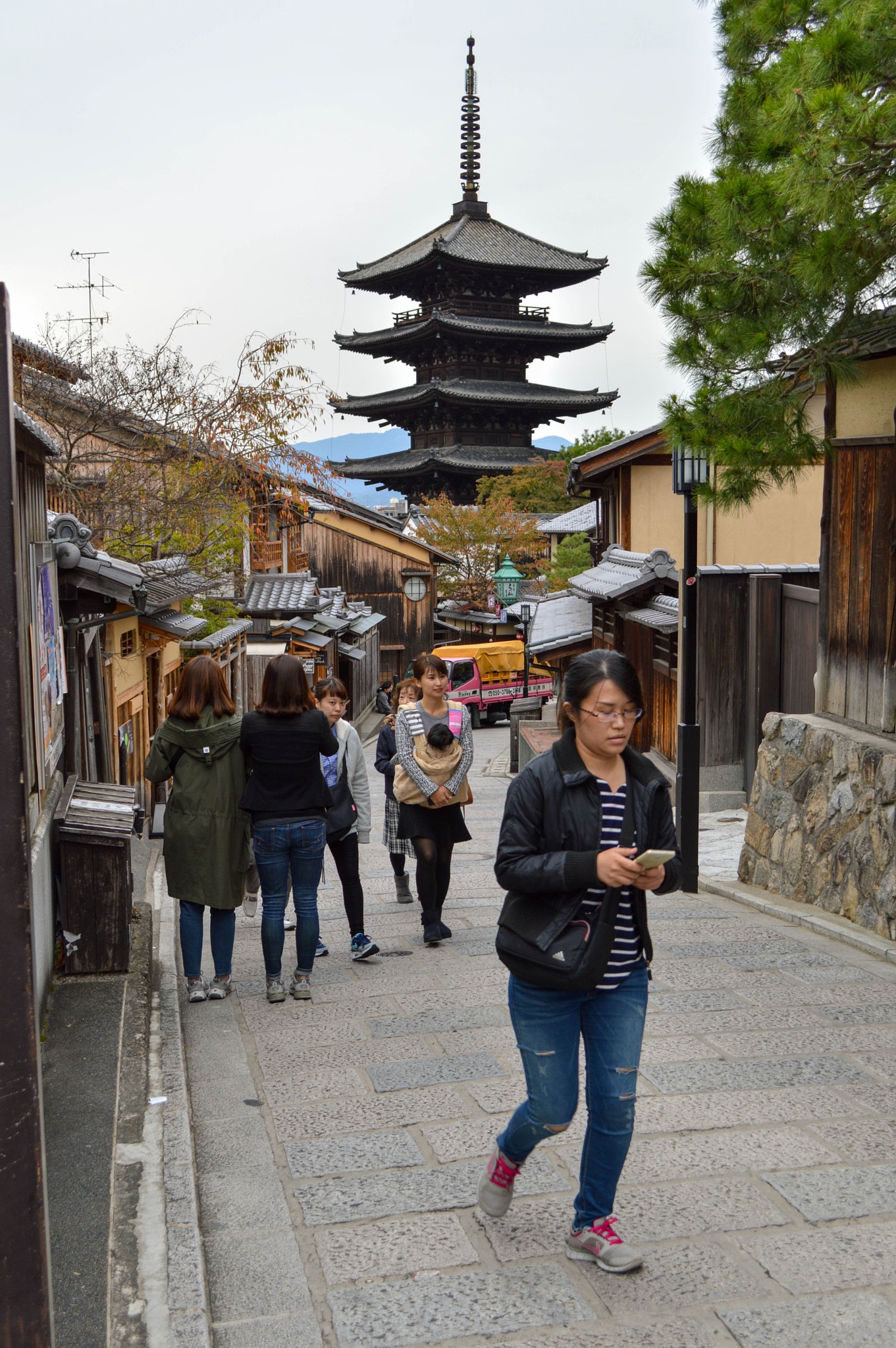 A person walking outdoors while texting on a smartphone held in both hands