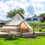 Bell tent on a wooden deck with outdoor furniture at a glamping site