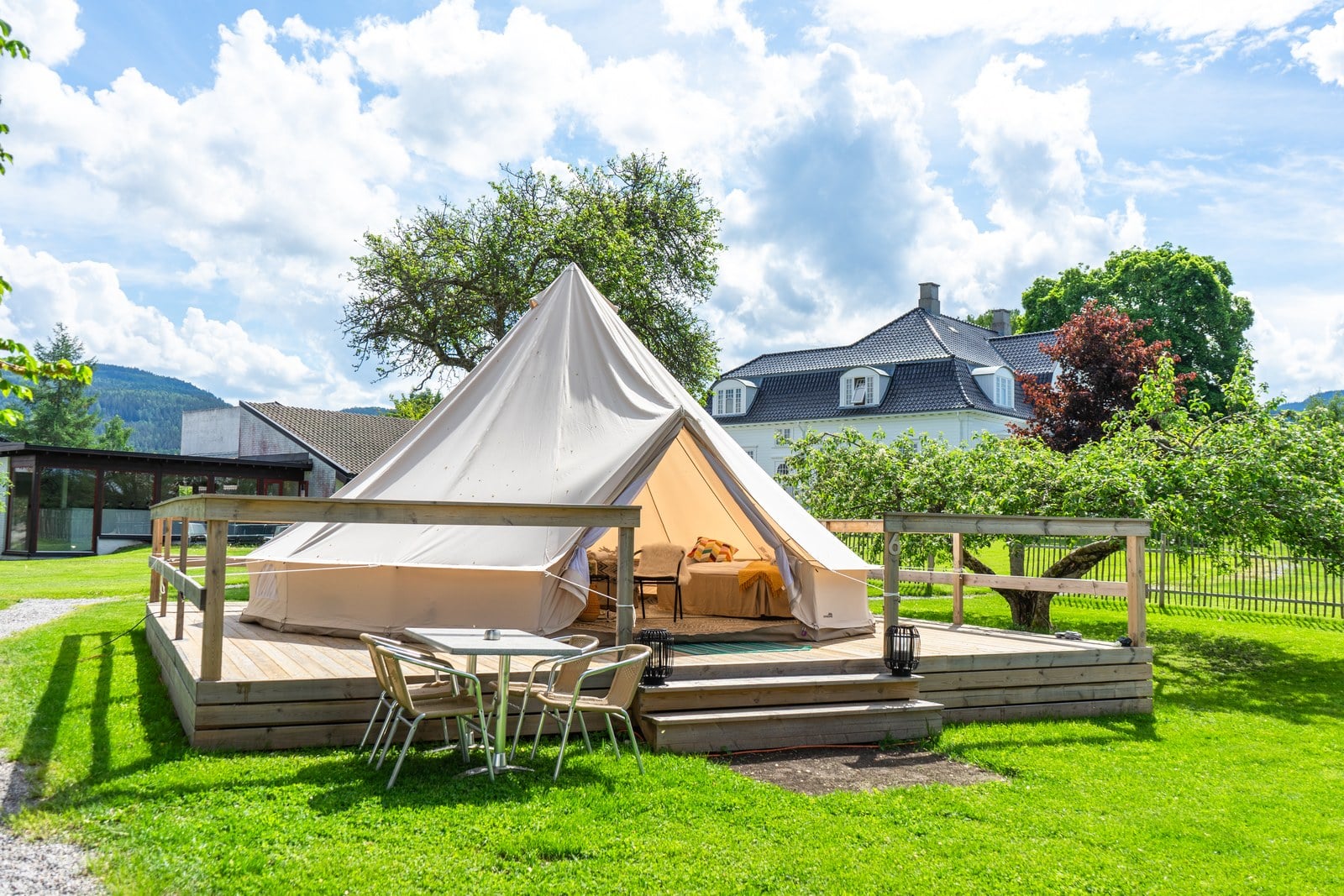 Bell tent on a wooden deck with outdoor furniture at a glamping site