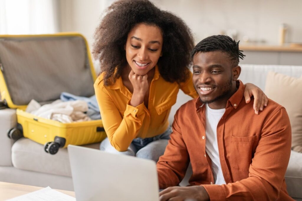 Couple reviewing travel documents and a laptop while planning a trip