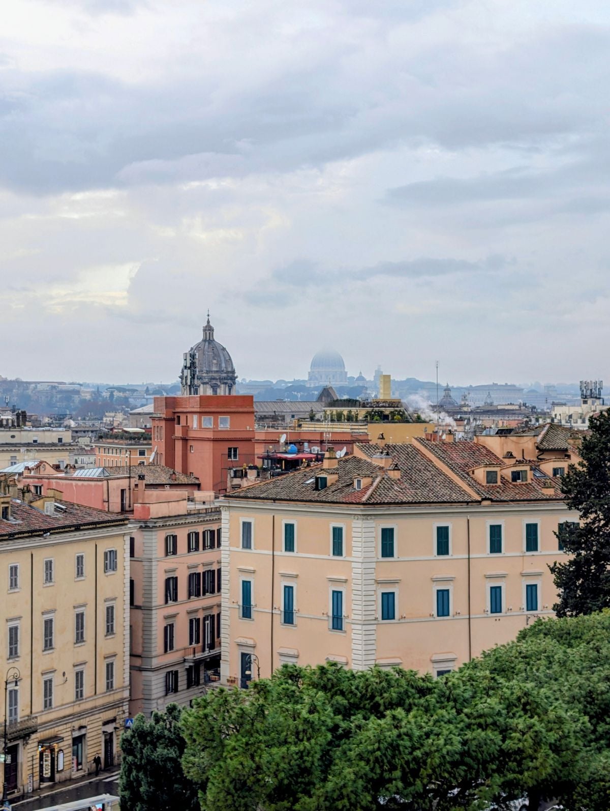Historic rooftops and domes of Rome under a cloudy sky, viewed from above