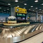 Modern baggage claim area at Suvarnabhumi Airport in Bangkok with luggage carousel and signage.