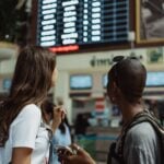 Traveler at an airport departure board checking a delayed domestic flight