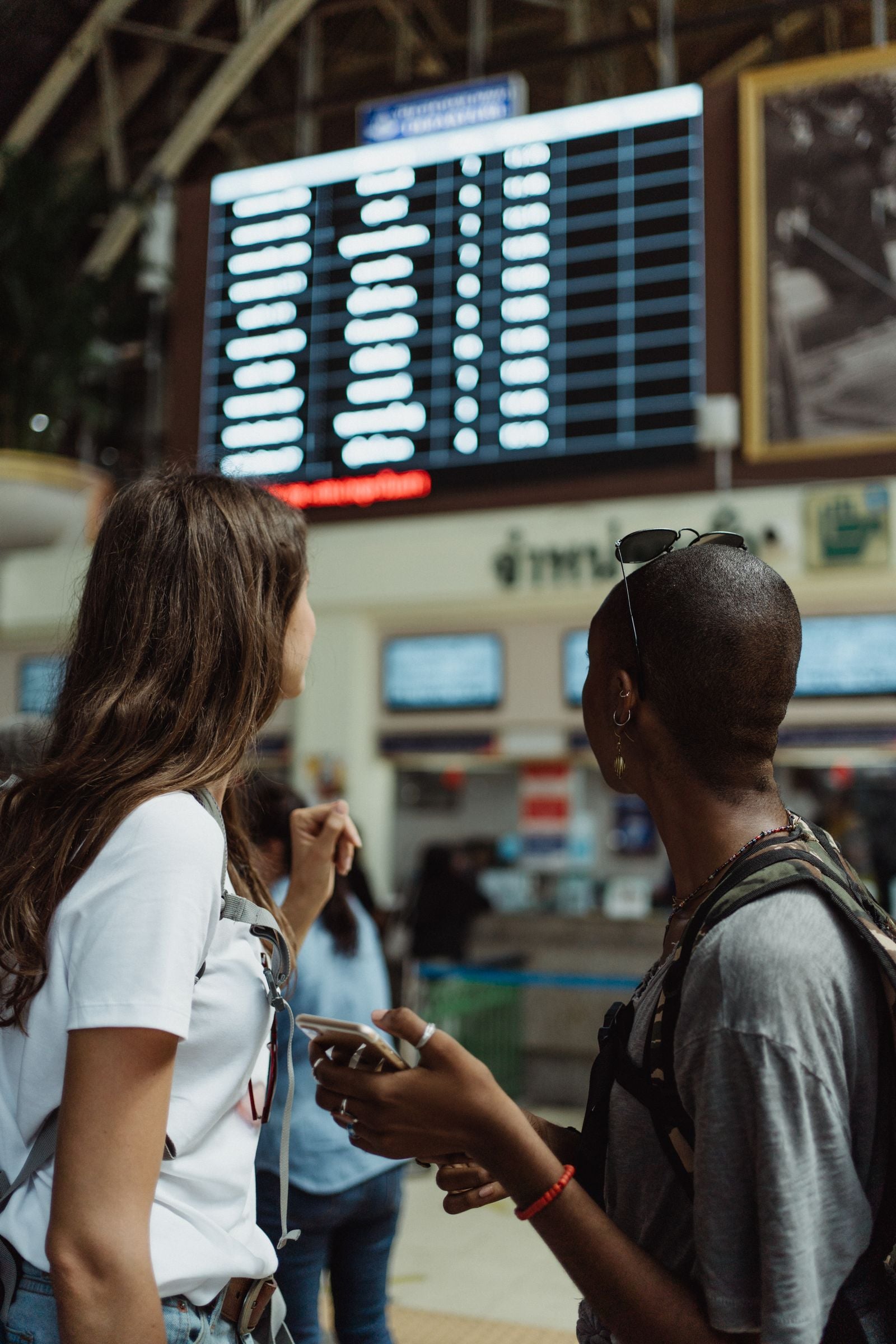 Traveler at an airport departure board checking a delayed domestic flight