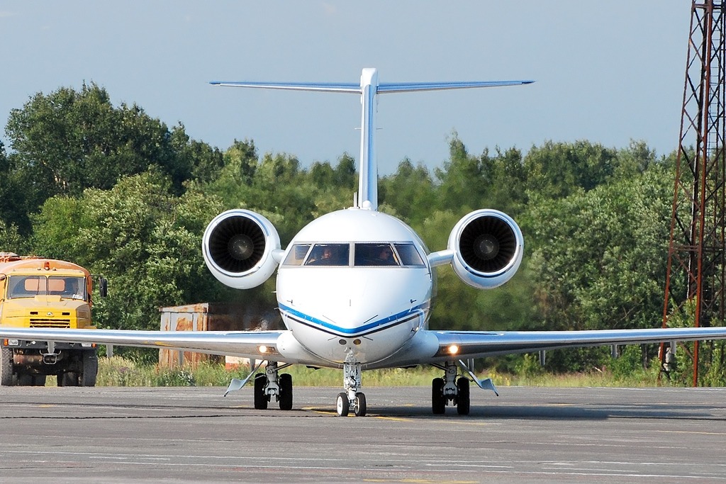 A white Bombardier Challenger 604 private jet parked head-on on an airport tarmac