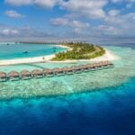 Aerial view of overwater private pool villas in turquoise water in the Maldives