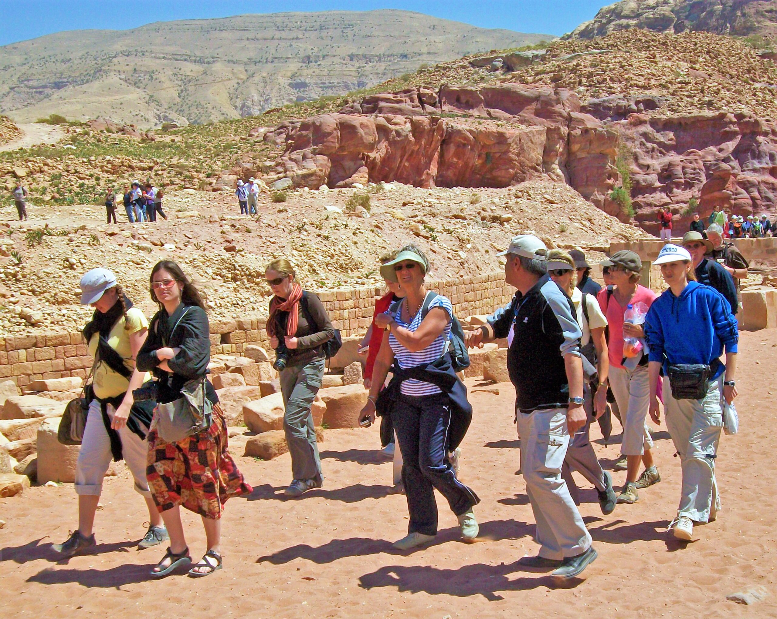 Tourists walking with a guide through a desert canyon at Petra, Jordan