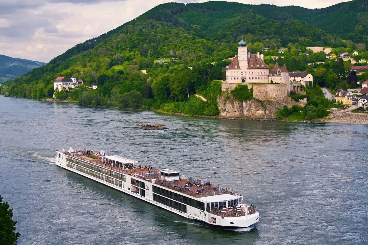 Viking river cruise longship sailing on the Danube past a hilltop castle