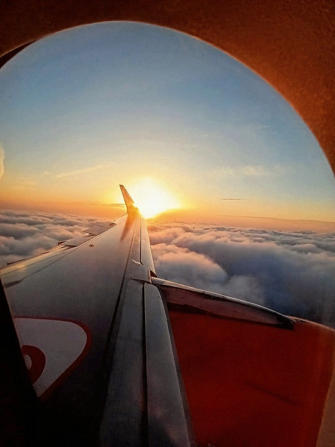 Sunset view from an airplane window above the clouds