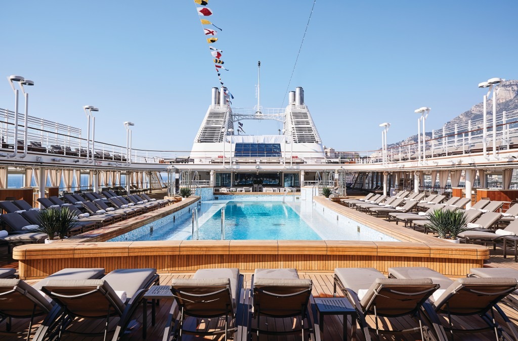The pool deck of a Silversea cruise ship with loungers, umbrellas and the ocean beyond