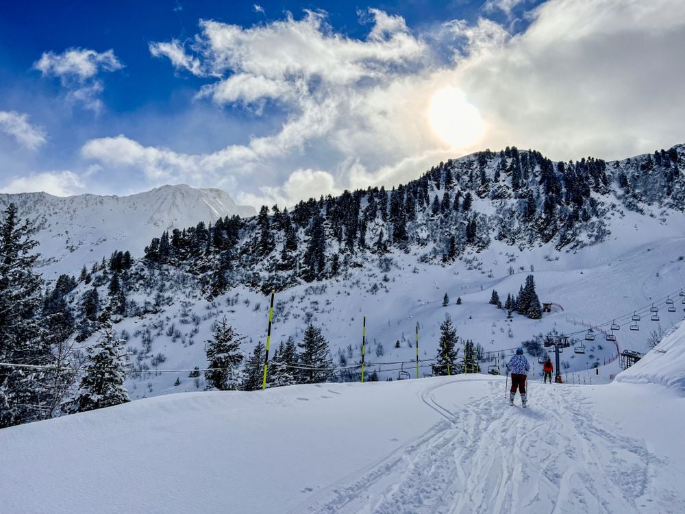Winter scene of skiers on a scenic snowy mountain with blue sky and pine trees