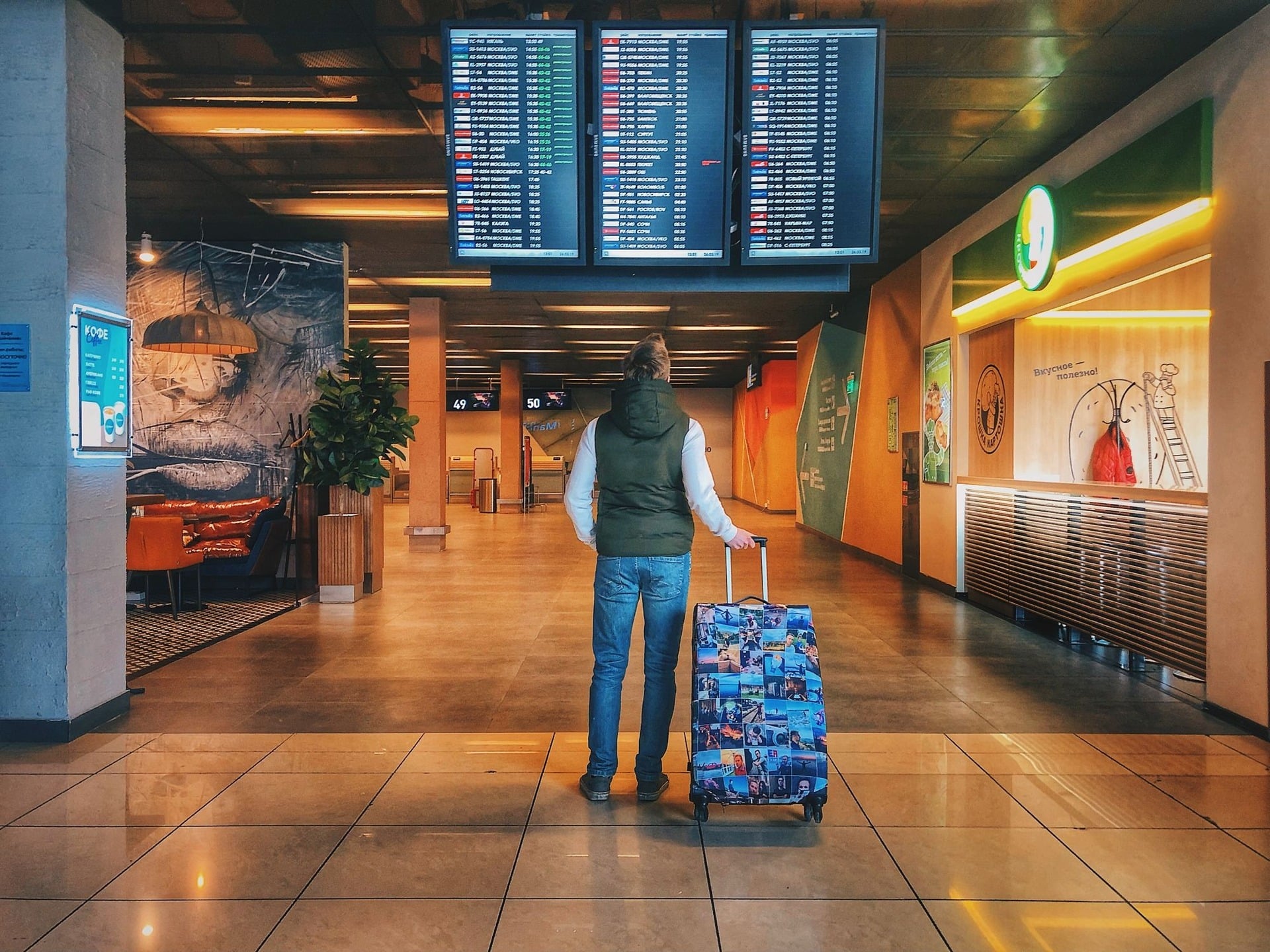 Traveler with rolling luggage walking through a modern airport terminal